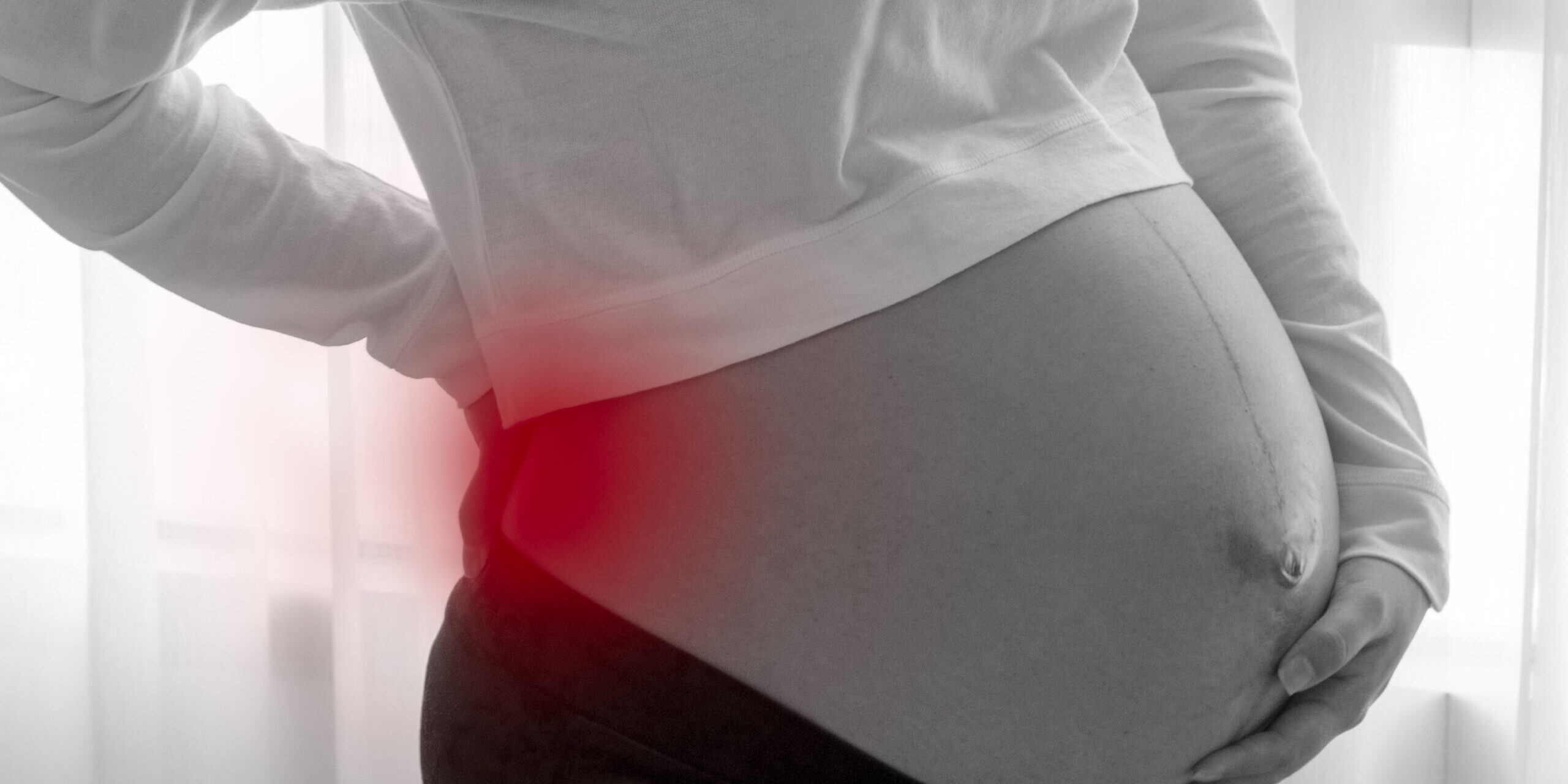 pregnant women having back ache from weight of baby before birth black and white