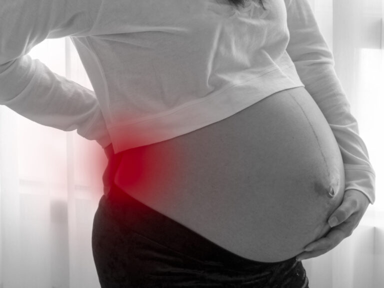 pregnant women having back ache from weight of baby before birth black and white