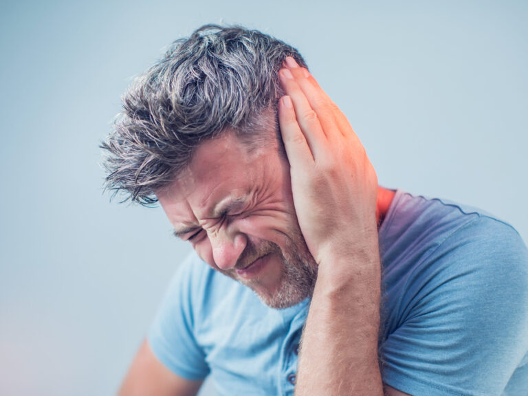 male having ear pain touching his painful head isolated on gray background